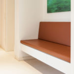 Garderobe mit lederbezogener Sitzbank, weißen Möbel und Nische in Eiche