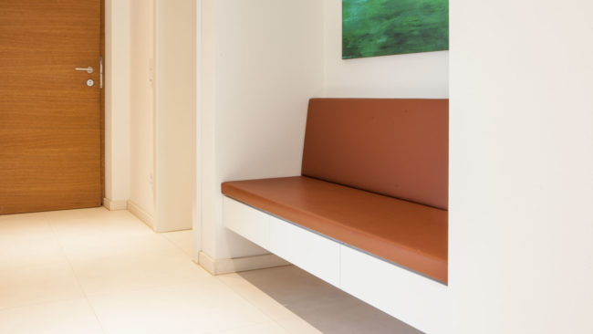 Garderobe mit lederbezogener Sitzbank, weißen Möbel und Nische in Eiche