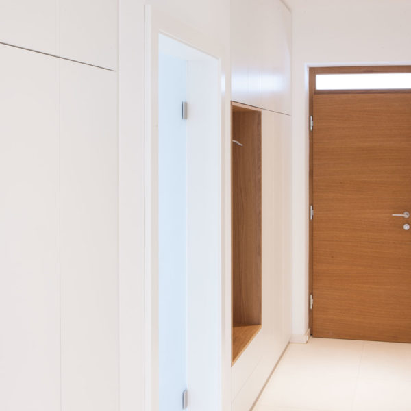 Garderobe mit lederbezogener Sitzbank, weißen Möbel und Nische in Eiche