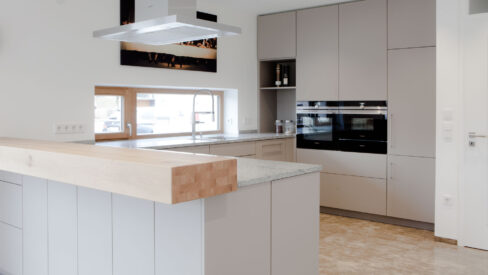 Küche in grau mit Frühstückstresen aus massivem Holz