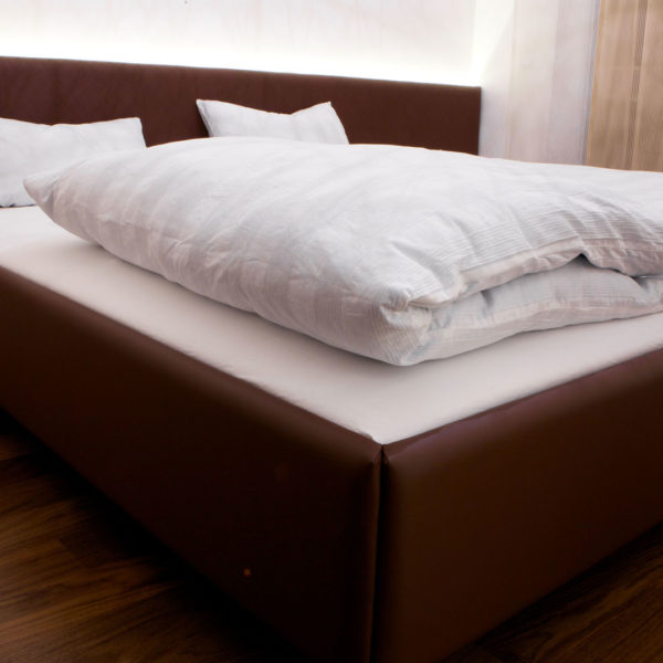 Bett gepolstert und mit Leder überzogen