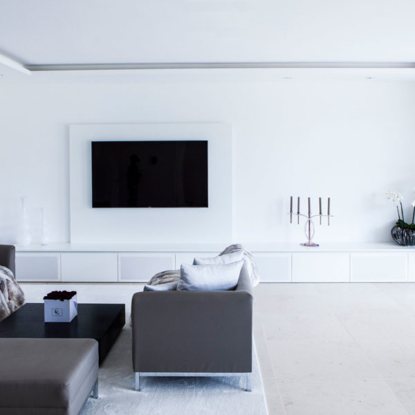 Wohnzimmer in weiß mit großem TV-Schrank und integriertem Soundsystem