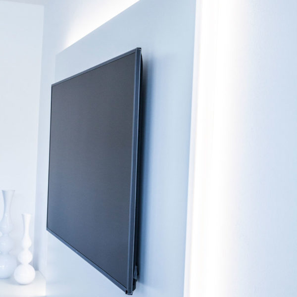 Wohnzimmer in weiß mit großem TV-Schrank und integriertem Soundsystem