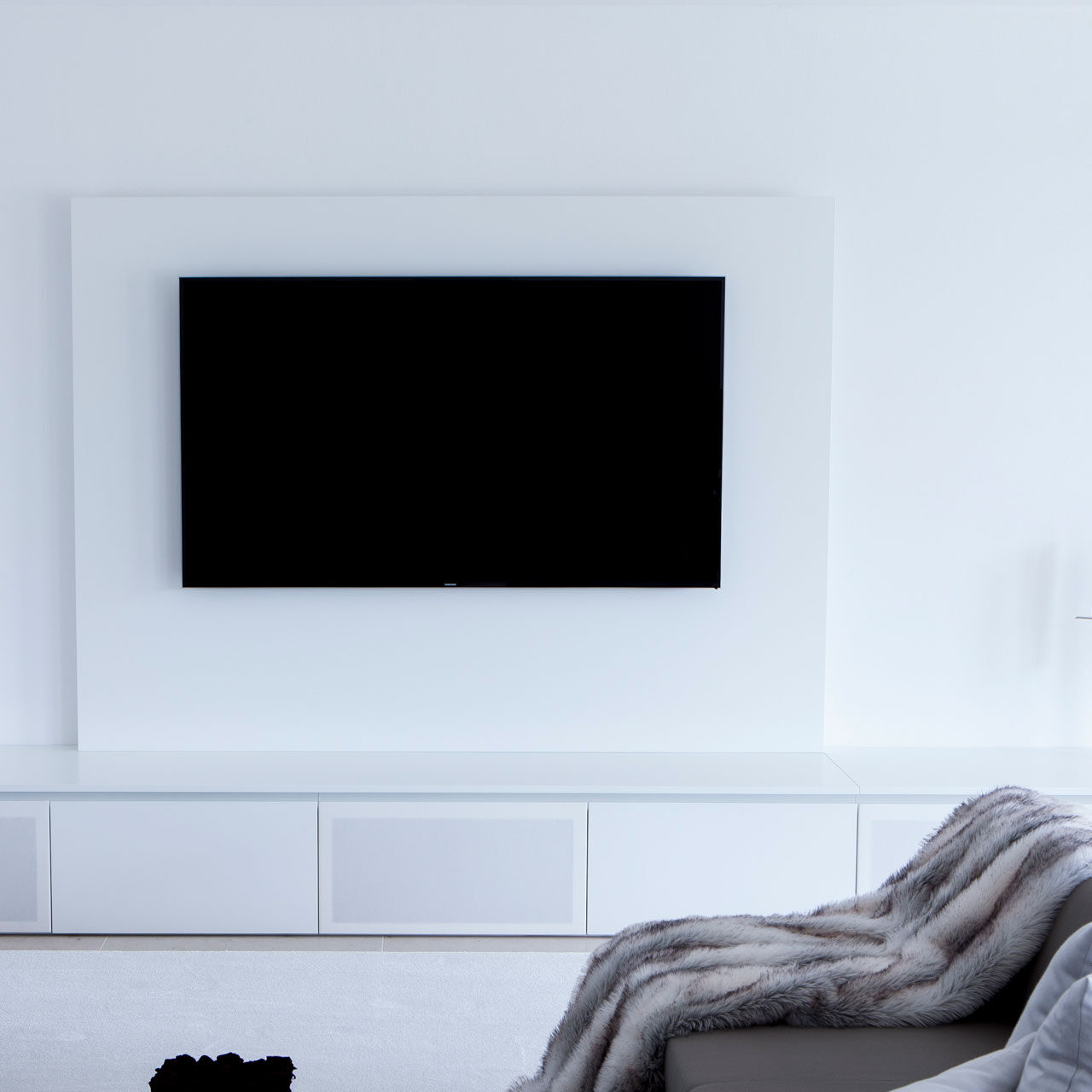 Wohnzimmer in weiß mit großem TV-Schrank und integriertem Soundsystem