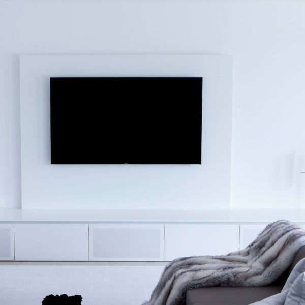 Wohnzimmer in weiß mit großem TV-Schrank und integriertem Soundsystem