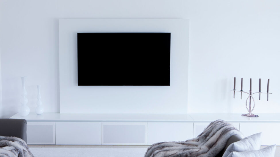 Wohnzimmer in weiß mit großem TV-Schrank und integriertem Soundsystem