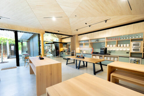 Modern gestalteter Thekenbereich mit offenen Regalen, Selbstbedienungstheke und viel Tageslicht in einer Café- oder Restaurantumgebung.