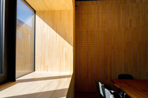 Stimmungsvolle Ecke eines Gastraums mit großem Fenster, warmem Lichteinfall und hölzernem Fenstersims.