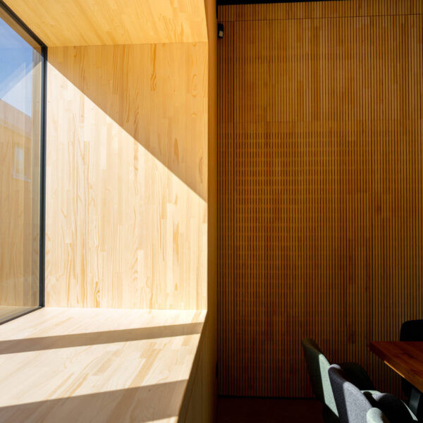 Stimmungsvolle Ecke eines Gastraums mit großem Fenster, warmem Lichteinfall und hölzernem Fenstersims.