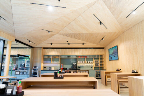 Heller Innenraum mit modernem Selbstbedienungsbereich, ausgestattet mit Holzdecken und minimalistischen Möbeln.