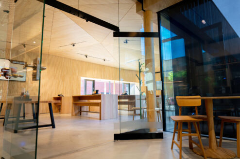 Blick durch eine Glastür auf einen freundlich gestalteten Gastraum mit klaren Linien und Holzoptik.