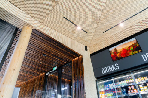 Moderne Deckengestaltung in Kombination mit rustikalem Holz und einem gut sortierten Getränke-Kühlregal.