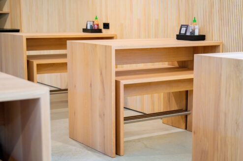 Nahaufnahme eines kompakten Holztischs mit integrierter Fußablage, perfekt für kleine Sitzgruppen.