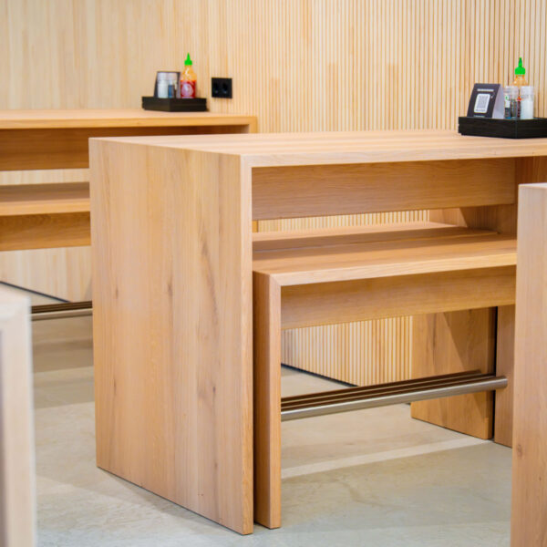 Nahaufnahme eines kompakten Holztischs mit integrierter Fußablage, perfekt für kleine Sitzgruppen.