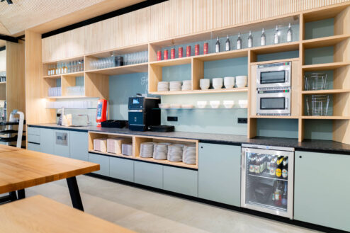 Übersicht des Selbstbedienungsbereichs mit Tellern, Gläsern, Mikrowellen und Kaffeeautomat in klarer, funktionaler Anordnung.