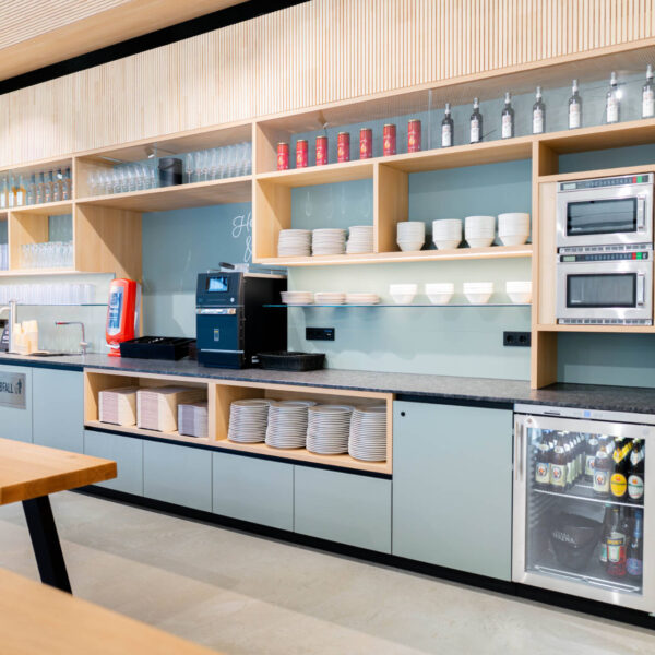 Übersicht des Selbstbedienungsbereichs mit Tellern, Gläsern, Mikrowellen und Kaffeeautomat in klarer, funktionaler Anordnung.