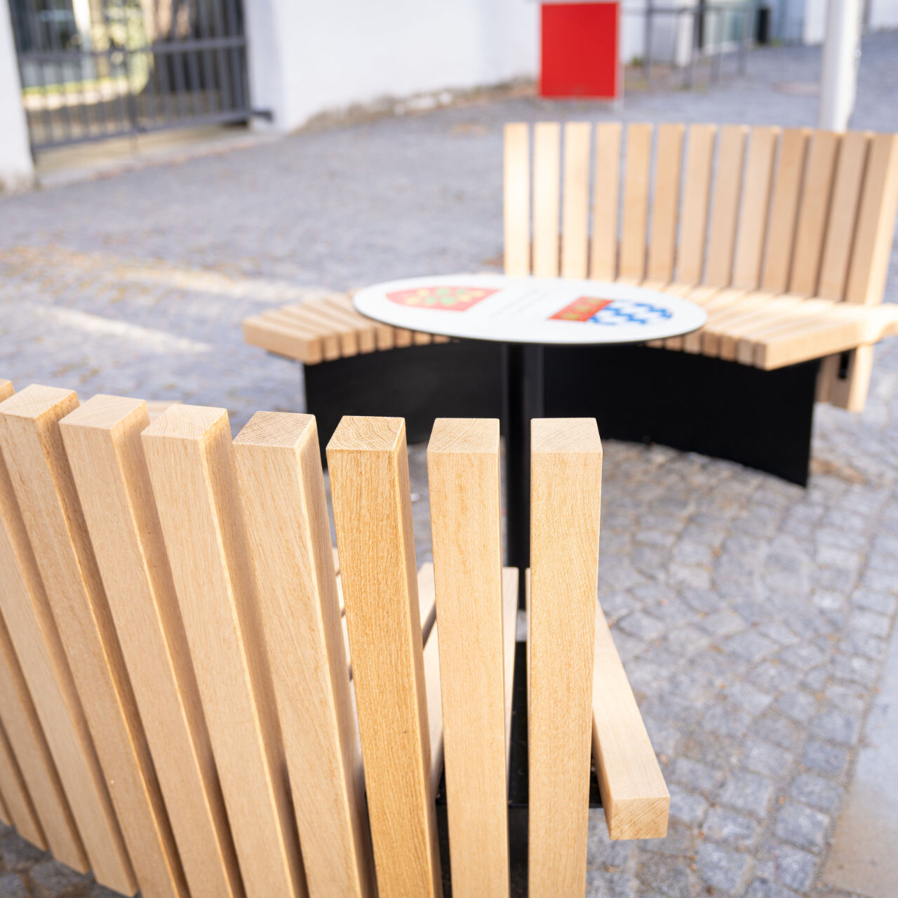 Zwei halbrunde Sitzbänke aus Holz mit Tisch in der Mitte, fotografiert aus der Vogelperspektive.