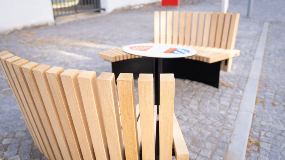 Zwei halbrunde Sitzbänke aus Holz mit Tisch in der Mitte, fotografiert aus der Vogelperspektive.