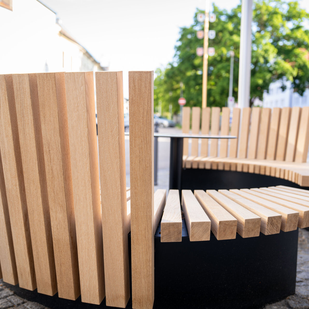 Moderne Rundbank aus Holz mit vertikalen Lamellen.