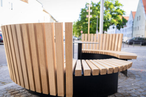 Moderne Rundbank aus Holz mit vertikalen Lamellen.