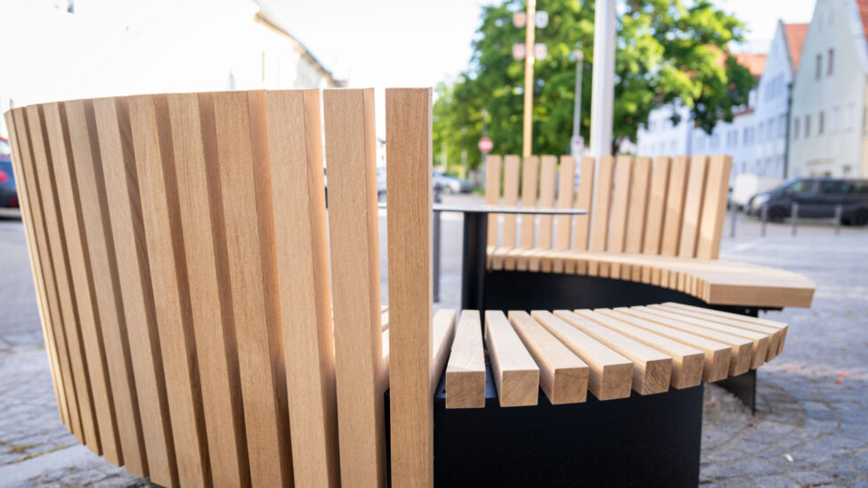 Moderne Rundbank aus Holz mit vertikalen Lamellen.